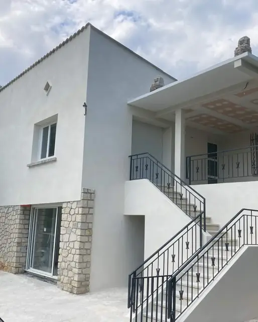Après travaux : façade rénovée, enduit blanc et escalier extérieur