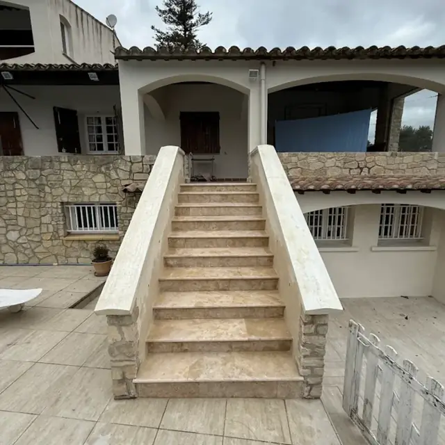 Escalier extérieur maçonné habillé de pierre menant à une terrasse couverte