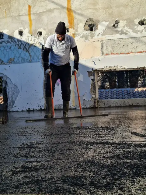 Maçon de Pontes Maçonnerie en train de tirer une dalle béton sur un chantier