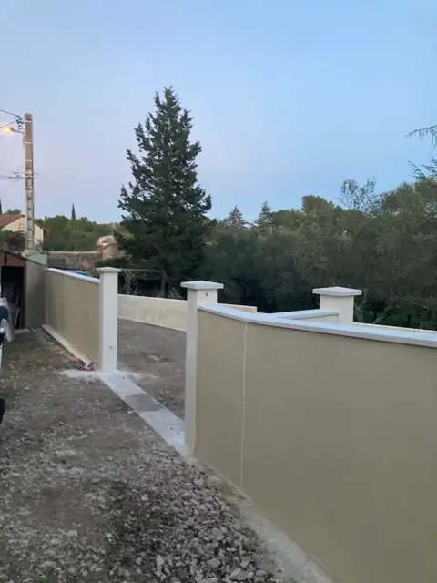 Mur de clôture enduit avec piliers et chaperons