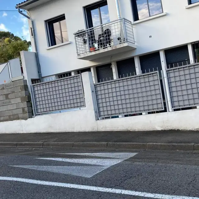 Mur de clôture maçonné surmonté de panneaux, en bordure de rue