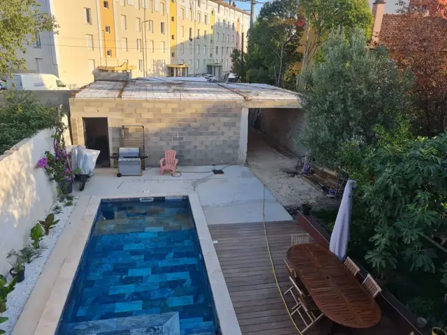 Piscine avec plage et terrasse aménagées dans un jardin du Gard